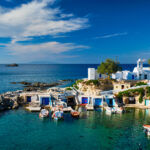 Typical Greece scenic island view - small harbor with fishing boats in crystal clear turquoise water, traditional white houses church. Mandrakia village, Milos island, Greece.